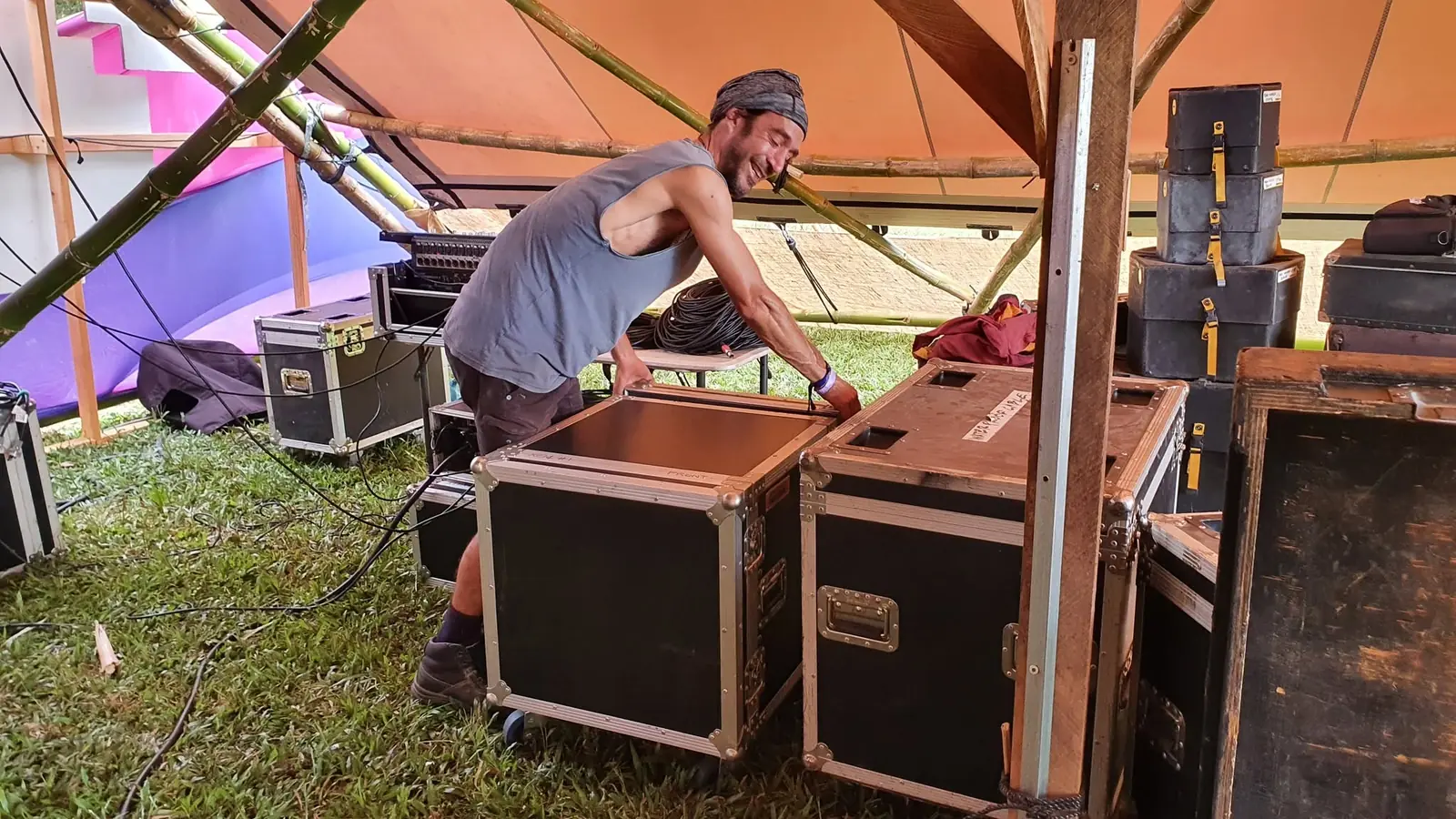 Crew setting up flight-cased equipment under a stage canopy