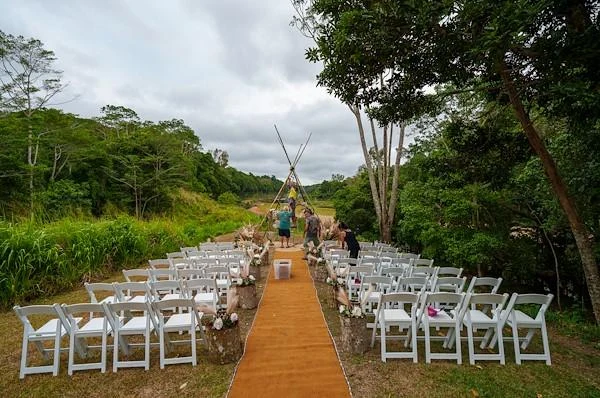 Outdoor wedding ceremony aisle and white chairs surrounded by tropical greenery in Kuranda